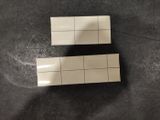 two pieces of white tile sitting on top of a black table