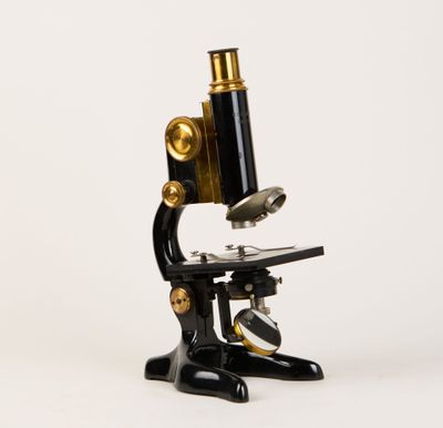 un gros plan d'un microscope noir et doré sur fond blanc