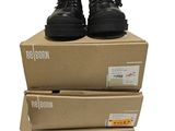 trois boîtes empilées les unes sur les autres, sur lesquelles se trouve une paire de bottes noires