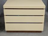 a white chest of drawers sitting on top of a cement floor