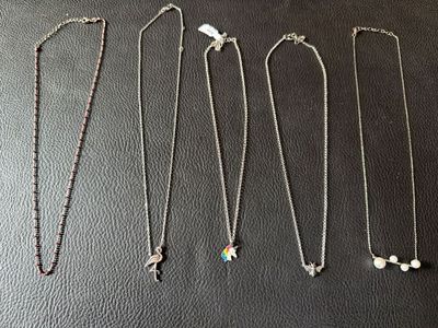 a group of four necklaces sitting on top of a black surface