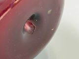 un gros plan d'un vase rouge percé d'un trou