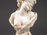 a white marble busturine of a woman holding a flower