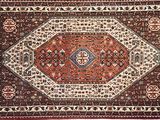 un tapis persan ancien aux motifs rouges, blancs et bleus