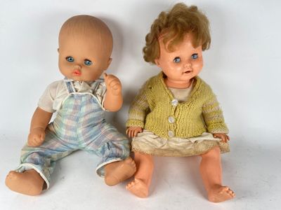 two dolls sitting next to each other on a white surface