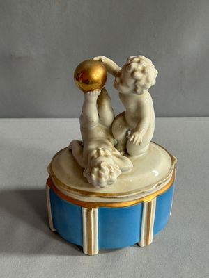 figurine en porcelaine représentant deux chérubins, posée sur une boîte bleue et blanche