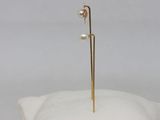 a white pillow with a gold earring on top of it