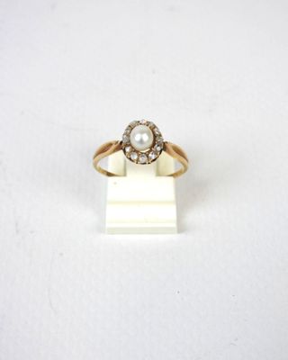 gros plan d'une bague en or avec une perle et des diamants