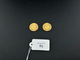 une paire de pièces d'or avec une étiquette de prix posée sur une surface noire