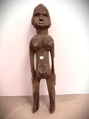 statue of a man with a hat on his head standing in front of a white wall