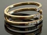 two gold rings with diamonds on a black surface