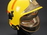 yellow fireman ' s helmet on a black stand against a black background