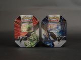Deux boîtes de jouets Pokémon sont posées côte à côte sur une surface noire.