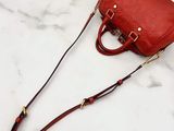 red leather handbag on a marble surface with a black handle