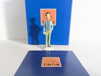 une petite figurine représentant un homme debout devant un livre bleu