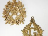 two gold masonic symbols are shown on a white surface