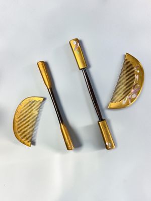 trois peignes dorés et une paire de ciseaux posés sur une surface blanche