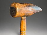 an old wooden mallet with a wooden handle on a gray background