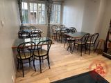 des tables et des chaises dans une pièce, avec une bibliothèque en arrière-plan
