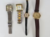 trois montres et une montre-bracelet sont posées sur une surface blanche