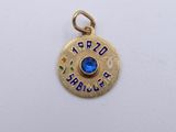 a close up of a gold plated charm with a blue stone