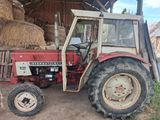 a tractor that is parked in a barn with hay on the ground