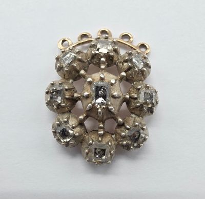 un gros plan d'une broche en or et diamants posée sur une surface blanche