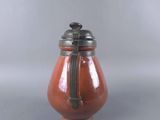 a small red vase with a metal lid