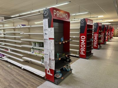 de nombreuses étagères vides dans un magasin, sur lesquelles figurent les prix