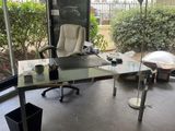 a glass desk with a laptop on it in the corner of a room
