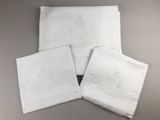 quatre serviettes blanches ornées de motifs brodés, posées sur une table
