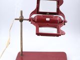 un petit objet rouge posé sur un socle, muni d'une loupe