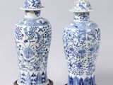 pair of blue and white vases with lids on wooden bases