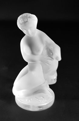black and white photograph of a figurine of a woman sitting on a stool