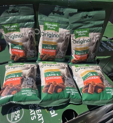 quatre sacs de croquettes pour chien posés sur une étagère dans un magasin