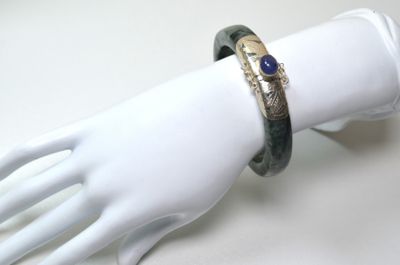 une main de mannequin blanche tenant un bracelet orné d'une pierre bleue