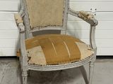 Une vieille chaise dont l'assise est abîmée est posée devant la porte d'un garage.