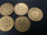four different types of gold coins on a black surface