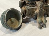 a statue of a man sitting on a chair next to a bowl