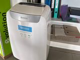 a small air conditioner sitting on the floor next to a bookshelf