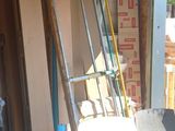 Plusieurs chaises et échelles sont empilées dans un garage