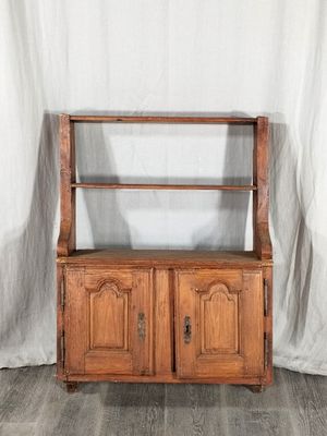 une vieille armoire en bois à deux portes, avec une étagère sur le dessus