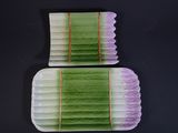 pair of green and white plates with decorative designs on them on a black surface