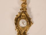 a gold clock hanging on the wall with a bird on it