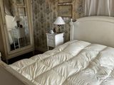 un lit blanc avec une couette blanche et un miroir dans un coin