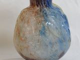 a blue and brown vase sitting on a white surface