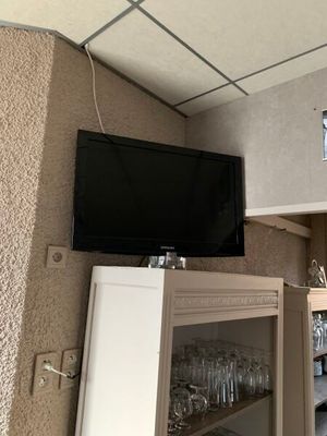 une télévision accrochée au mur au-dessus d'un meuble contenant des verres à vin
