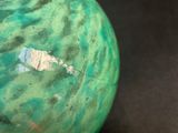 a green ball with a hole in it on a table