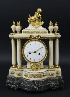 une horloge blanche et dorée posée sur un socle en marbre