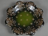 a black plate with a green center surrounded by brown and white flowers